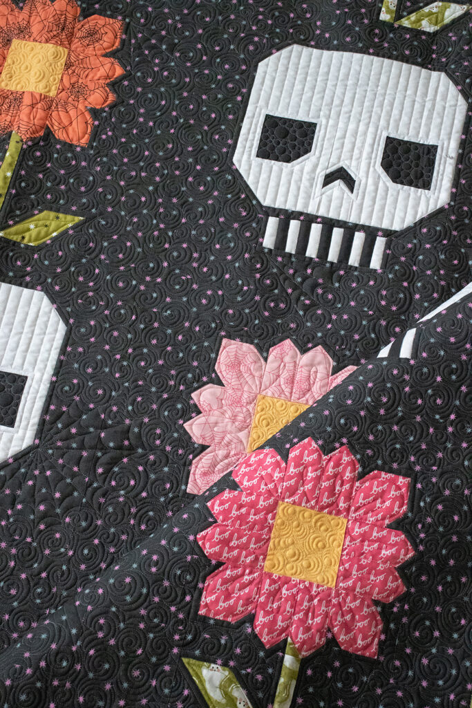 Pushing Up Daisies skull and flower Halloween quilt by Vanessa Goertzen of Lella Boutique. Would make a great Dia de los Muertos quilt in Hey Boo fabric by Lella Boutique for Moda Fabrics (arriving to shops April 2024). Download the PDF here!