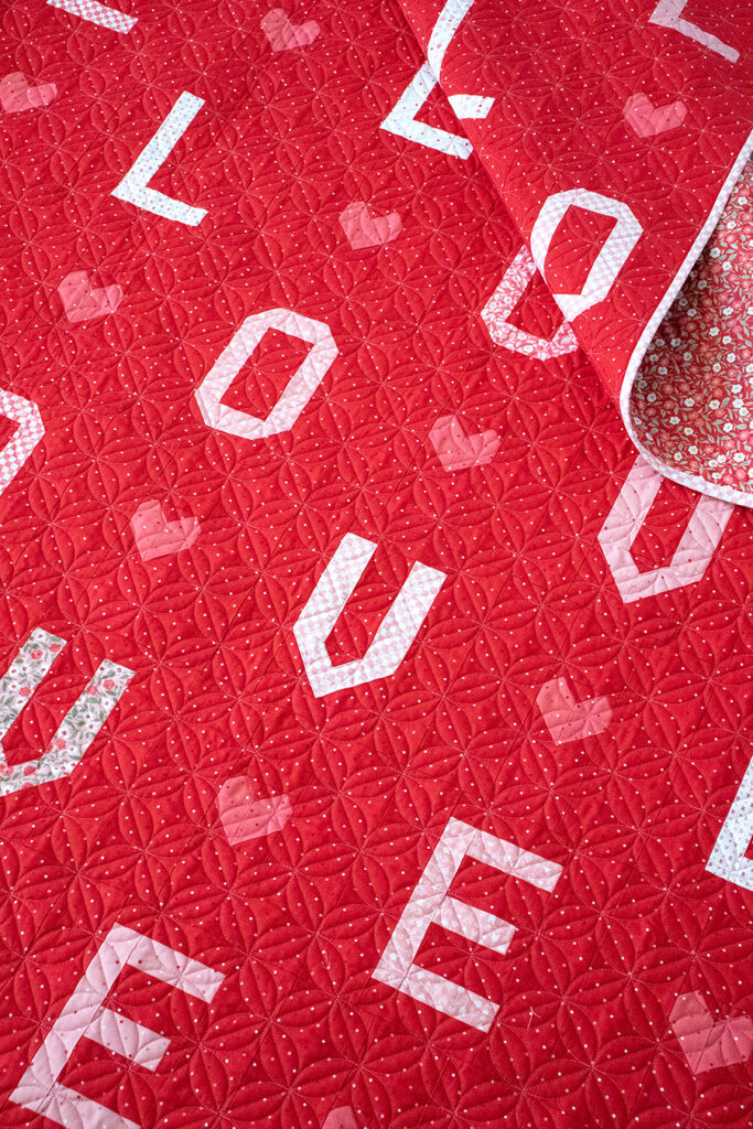 L-O-V-E word scramble quilt in Love Blooms fabric by Lella Boutique for Moda Fabrics. Such a fun valentines letter quilt! Download the PDF here.
