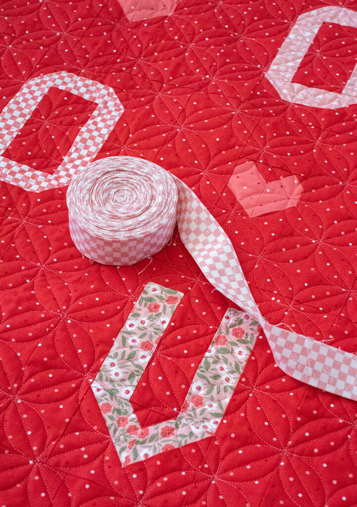 L-O-V-E word scramble quilt in Love Blooms fabric by Lella Boutique for Moda Fabrics. Such a fun valentines letter quilt! Download the PDF here.