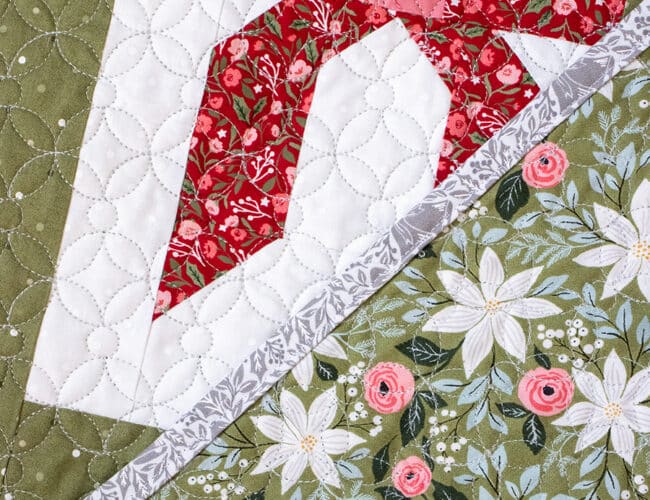 "Wrap it Up" wonky gift quilt in Berry & Pine fabric by Lella Boutique. Make it with fat quarters and fat eighths. The wonky Christmas present blocks get their offkilter look from a beginner partial-seam technique. Download the PDF here.