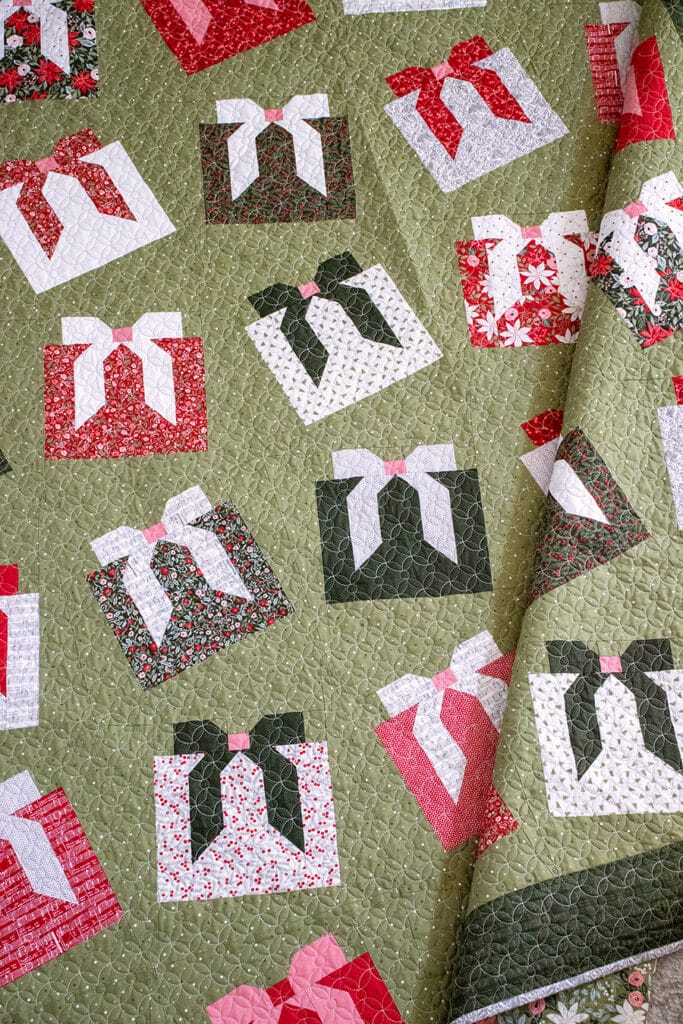 "Wrap it Up" gift quilt in Berry & Pine fabric by Lella Boutique. Make it with fat quarters and fat eighths. The wonky Christmas present blocks get their offkilter look from a beginner partial-seam technique. Download the PDF here.