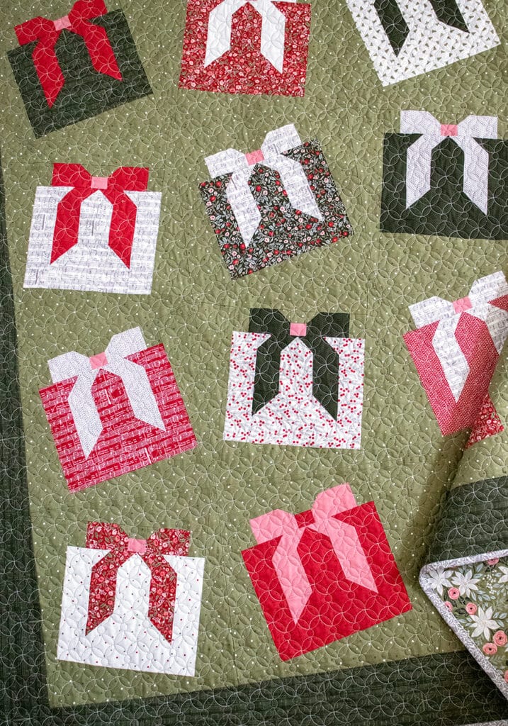 "Wrap it Up" gift quilt in Berry & Pine fabric by Lella Boutique. Make it with fat quarters and fat eighths. The wonky Christmas present blocks get their offkilter look from a beginner partial-seam technique. Download the PDF here.