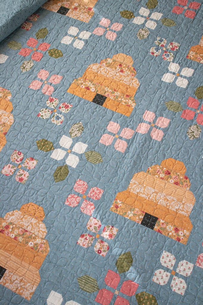 Bloom & Buzz beehive flower quilt by Lella Boutique. Jelly Roll friendly - fabric is Wild Honey by Lella Boutique for Moda Fabrics (Nov 2025). Download the PDF here!