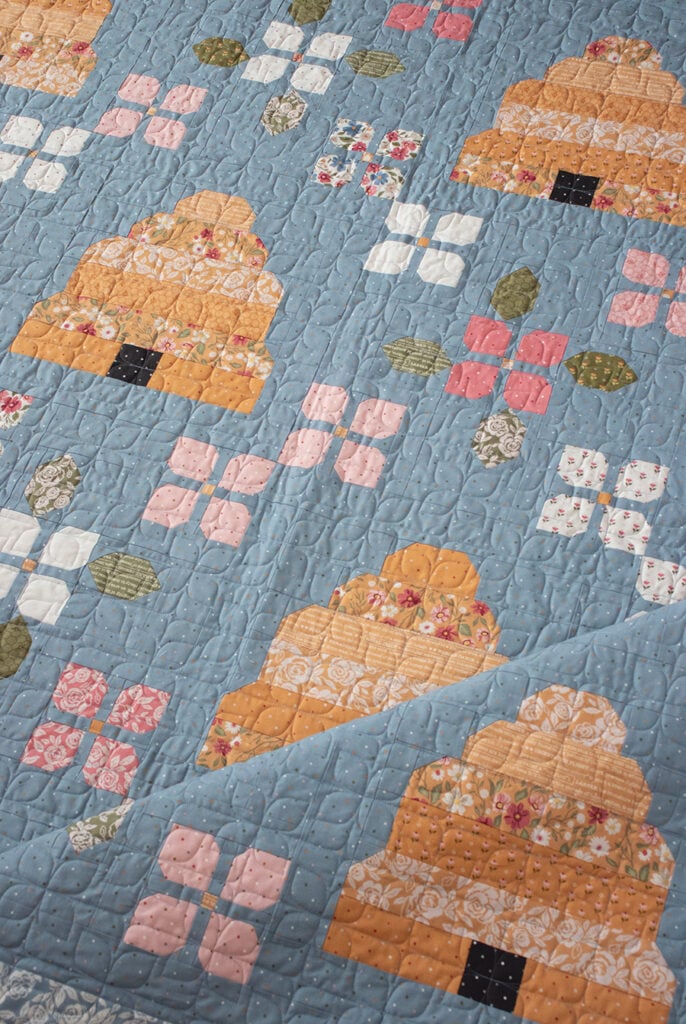 Bloom & Buzz beehive flower quilt by Lella Boutique. Jelly Roll friendly - fabric is Wild Honey by Lella Boutique for Moda Fabrics (Nov 2025). Download the PDF here!