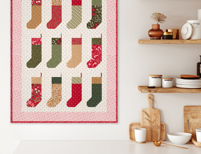 "By the Chimney Mini" stocking quilt wall hanging in Peppermint Cocoa by Lella Boutique for Moda Fabrics. Download the PDF here!