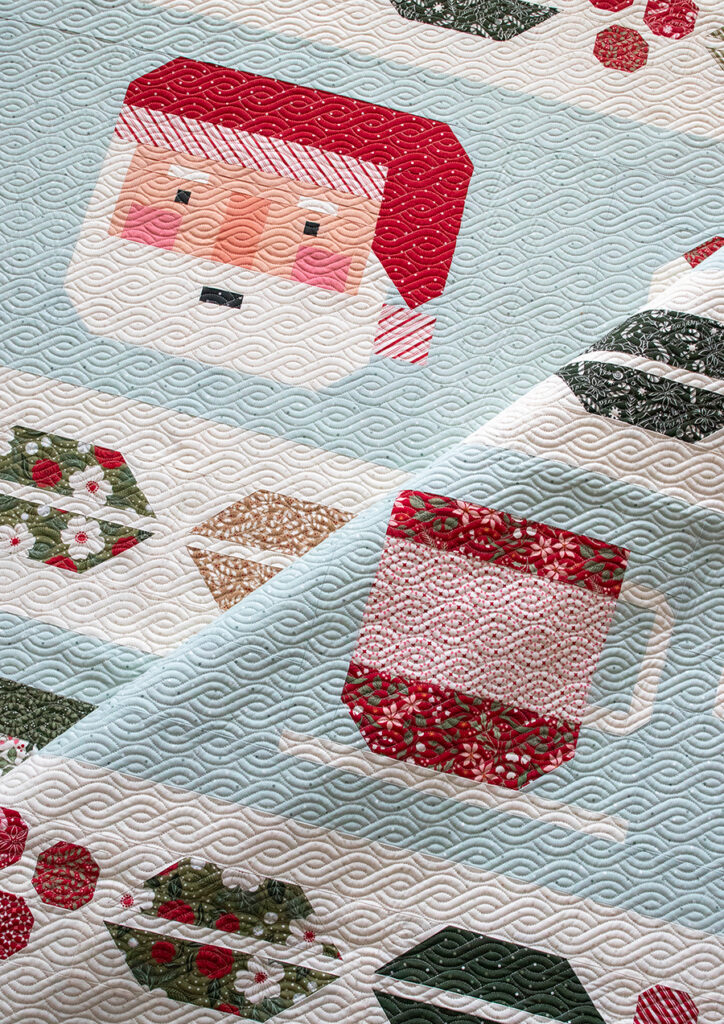 "Cocoa Party" Christmas row quilt by Vanessa Goertzen of Lella Boutique. Sampler includes patchwork Santa, cocoa mugs, marshmallows, and holly berry sashing. Fabric is Peppermint Cocoa by Lella Boutique for Moda Fabrics Download the PDF here!